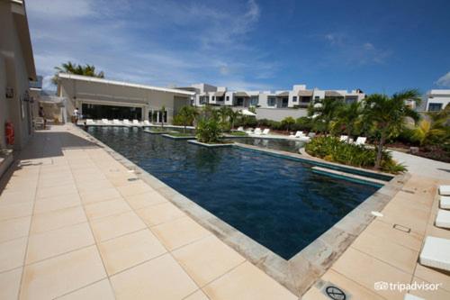 a large swimming pool in front of a house at AZURI Serviced Garden Apartment in Roches Noires