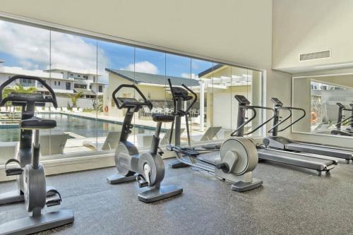 a gym with cardio machines and a large window at AZURI Serviced Garden Apartment in Roches Noires