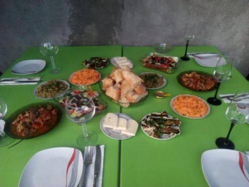 a green table topped with plates of food and wine glasses at Best Host in Sighnaghi