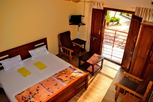 une chambre avec un lit, une chaise et une fenêtre dans l'établissement Club 7 Beach Resort, à Kannur