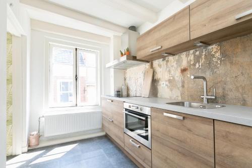 een keuken met houten kasten, een wastafel en een raam bij Fruit of the City - R.Q.C. in Den Haag