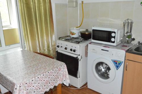 a kitchen with a washing machine and a microwave at Apartment on Bokonbaev street, 145 in Bishkek