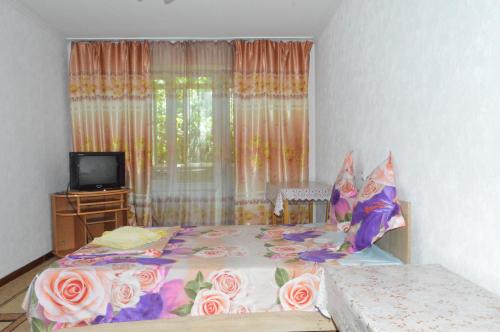 a bedroom with a bed and a tv and a window at Apartment on Bokonbaev street, 145 in Bishkek