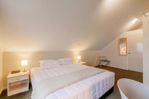 a bedroom with a large white bed and a chair at Le Chalet Suisse Motel Taupo in Taupo