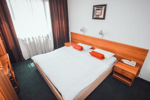 a bedroom with a bed with two red pillows on it at Hotel Grand in Sarajevo
