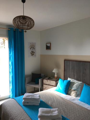 a bedroom with a large bed with blue pillows at La Belle Verte in Pornic