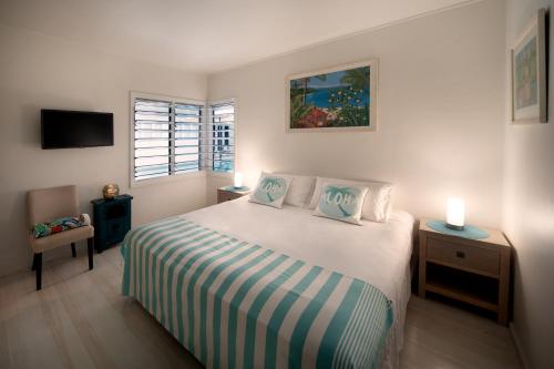 a bedroom with a bed and a television and two lamps at Bathers across the bay from Port Douglas in Newell Beach