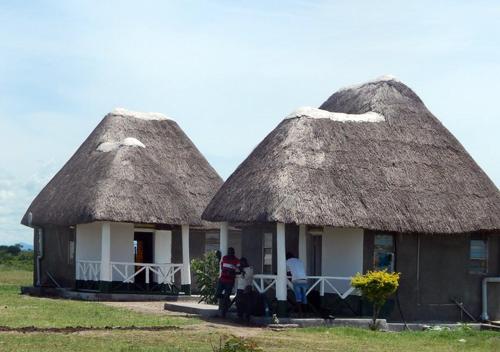 two small huts with people standing outside of them at Kasenyi Lake Retreat Lodges & Campsite in Kasese