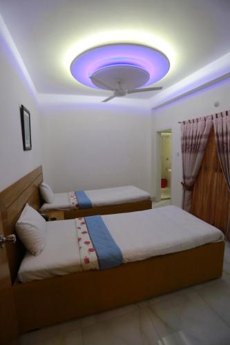 a bedroom with two beds and a ceiling with a purple light at Nagar Valley Hotel Ltd. in Dhaka