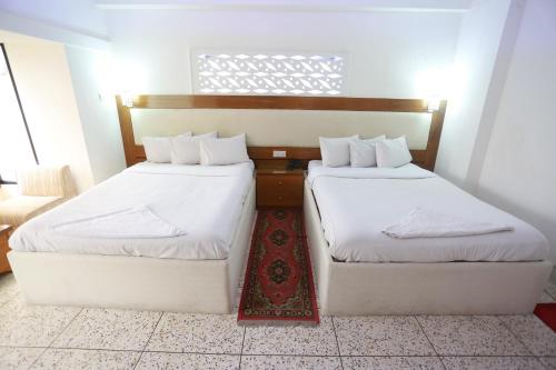 two twin beds in a room with a window at Nagar Valley Hotel Ltd. in Dhaka