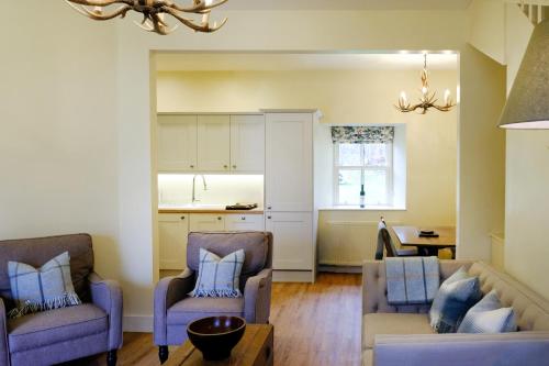 un salon avec deux chaises et un canapé dans l'établissement Luss Cottages at Loch Lomond Arms Hotel, à Luss