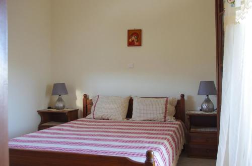 a bedroom with a bed with a striped blanket and two lamps at Limnes Home in Moutsoúna