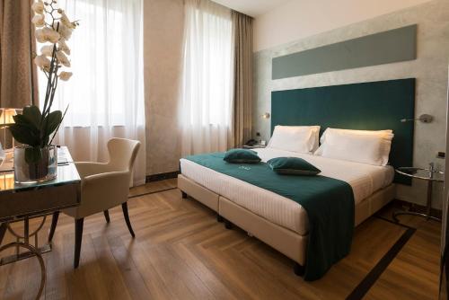 a bedroom with a bed with a green headboard and a table at Bianca Maria Palace Hotel in Milan