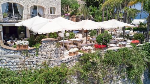 a restaurant with tables and white umbrellas and flowers at Hotel Ariston and Palazzo Santa Caterina in Taormina