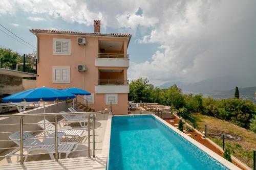 a villa with a swimming pool and a house at Apartments Mitrovic in Lustica