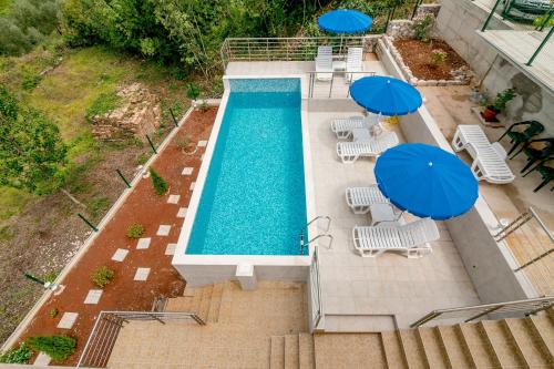 an overhead view of a swimming pool with blue umbrellas at Apartments Mitrovic in Lustica