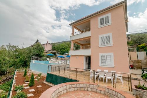 a house with a balcony and a swimming pool at Apartments Mitrovic in Lustica