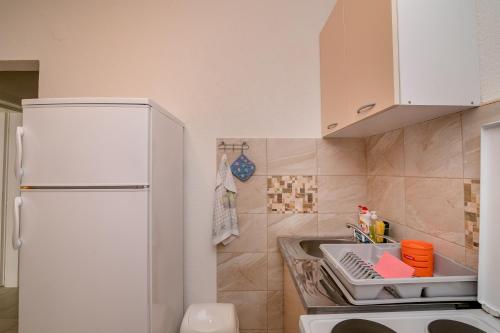 a kitchen with a white refrigerator and a sink at Apartments Mitrovic in Lustica