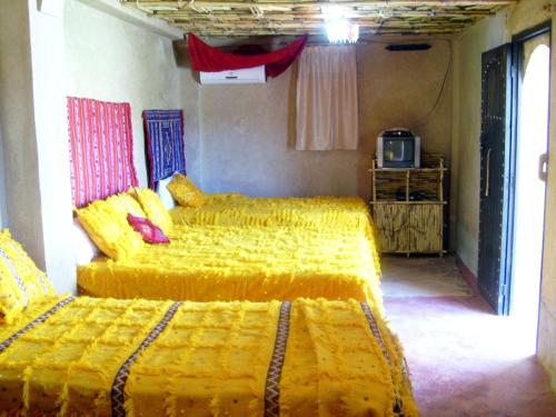 two beds in a room with yellow covers at Kasbah Dar Dmana in Skoura