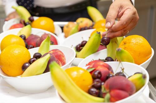 a person is reaching for fruit in bowls on a table at Hotel Ariston and Palazzo Santa Caterina in Taormina