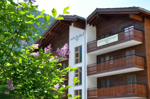 a building with balconies and trees in the foreground at Haus Mischabel in Zermatt