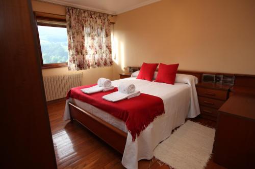 Un dormitorio con una cama con almohadas rojas y una ventana en Casa Rubieira, en Sequeiro