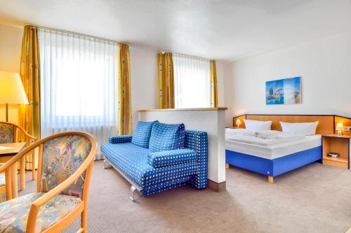 een slaapkamer met een bed, een bank en een stoel bij Strandhotel Bansiner Hof in Bansin