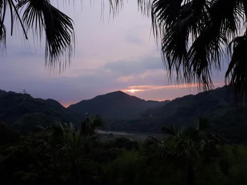 a sunset over a mountain range with a body of water at In Bali Inn in Luofu