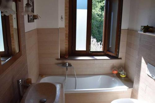 ヴォルテッラにあるTuscan home in Etruscan landscapeのバスルーム(バスタブ、シンク付)、窓が備わります。
