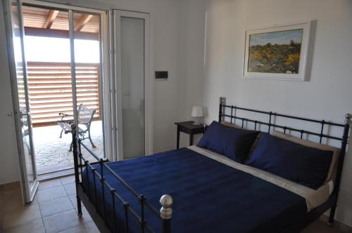 a bedroom with a bed with blue sheets and a balcony at Villetta La Lama in Torre Lapillo