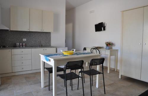 a kitchen with a white table with chairs and a counter at Villetta La Lama in Torre Lapillo