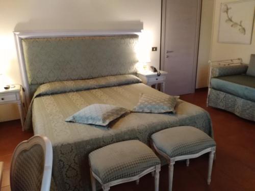 a bedroom with a large bed with two chairs at Hotel Antica Fenice in Campalto