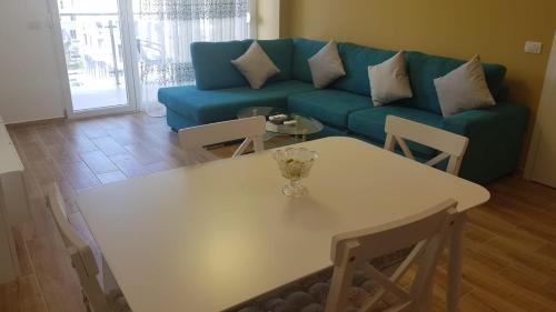 a living room with a white table and a blue couch at Shengjin - Helios Home in Shëngjin