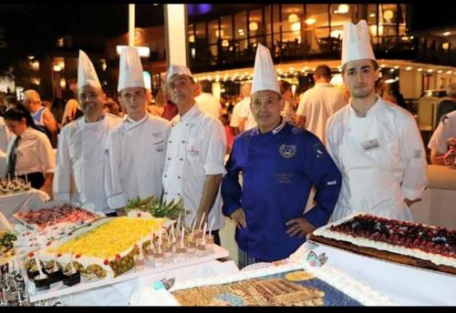 a group of chefs standing in front of a table with a cake at Hotel Gioiella Depandance in Bellaria-Igea Marina