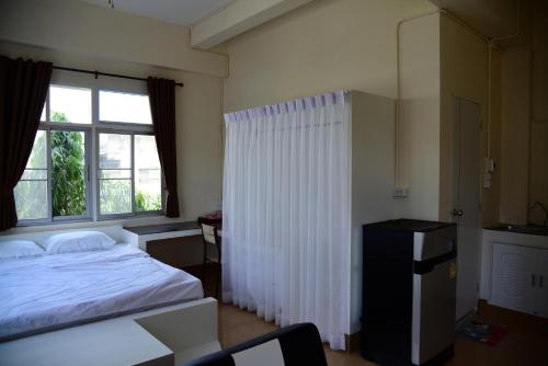 a bedroom with a white bed and a window at Tk Home 3 in Lampang