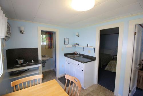 a kitchen with a sink and a table and a bed at Elmwood Motor Court in Old Orchard Beach