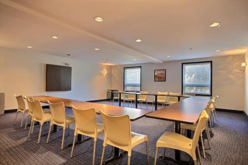 Una sala de conferencias con mesas, sillas y una pantalla. en Super 8 by Wyndham Lachenaie/Terrebonne, en Terrebonne