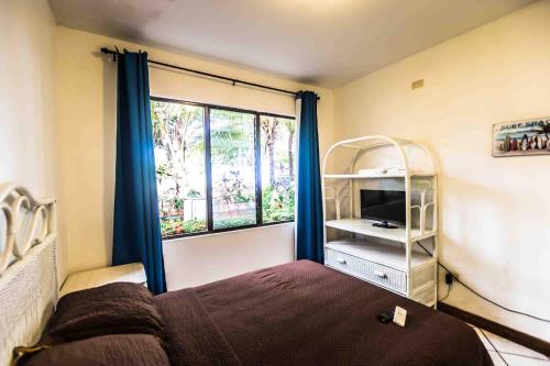 a bedroom with a bed with blue curtains and a window at La Dolce Vita in Esterillos