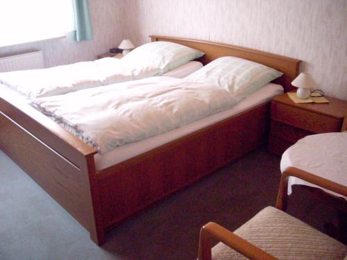 ゾルタウにあるHotel-Pension-Luisenhofのベッドルーム(白いシーツと木枠のベッド付)