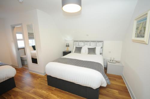 a white bedroom with a large bed and a mirror at Lodge at The Old Barracks in Athenry