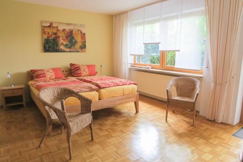 een slaapkamer met een bed en 2 stoelen en een raam bij Ferienwohnung Eibl in Donaustauf