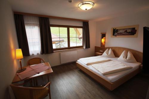 a bedroom with a bed and a desk and a window at Haus Dorfblick in Gerlos