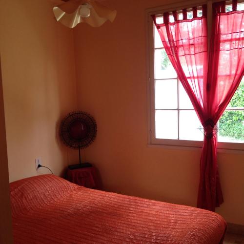 a bedroom with a red bed and a window at Location Saint Pierre d'Oléron in La Cotinière