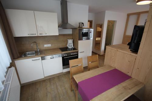a kitchen with white cabinets and a table with a purple table cloth at Haus Dorfblick in Gerlos