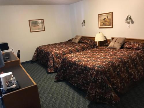 a hotel room with two beds and a television at The Home Hotel in Boissevain