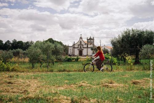 a woman riding a bike in front of a church at Chão do Rio - Turismo de Aldeia in Seia