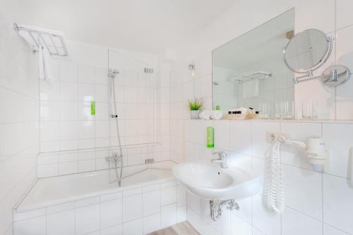 a white bathroom with a sink and a shower at Strandgrün Golf- & Spa Resort in Timmendorfer Strand