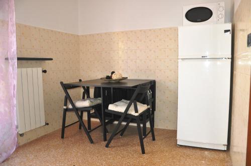 a black table with two chairs and a refrigerator at Viale Repubblica 307 4 in Pietra Ligure