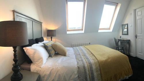 a bedroom with a bed and two windows at The Links Cottage in Lahinch