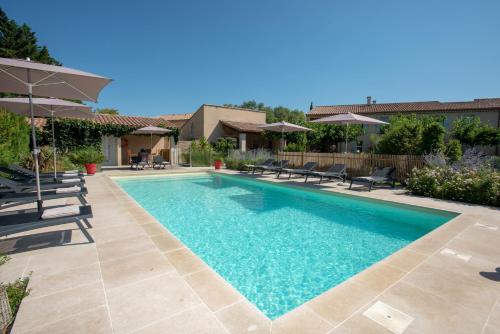 une piscine avec chaises et parasols dans une cour dans l'établissement Best Western Hôtel Aurélia, à Maussane-les-Alpilles